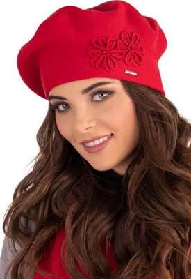 A woman wearing a red beret with flower embellishments.