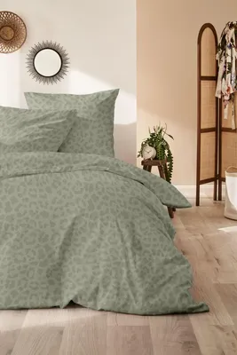 A bedroom scene with a bed dressed in green leopard-print bedding.