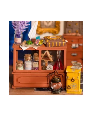 A miniature display of a magic shop with various potions, a book, and a lantern.