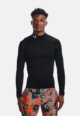 A man wearing a black long-sleeved shirt and patterned shorts against a white background.