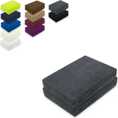 A stack of folded anthracite-colored fitted sheets is shown in the foreground, with smaller stacks of fitted sheets in various colors displayed in the background.