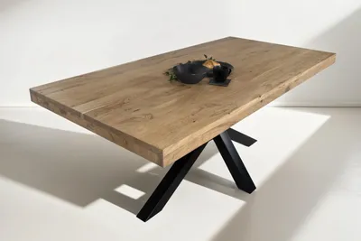 A rectangular wooden dining table with a black metal spider base, set against a white background.