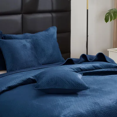 A close-up view of a bed with blue bedding and pillows.