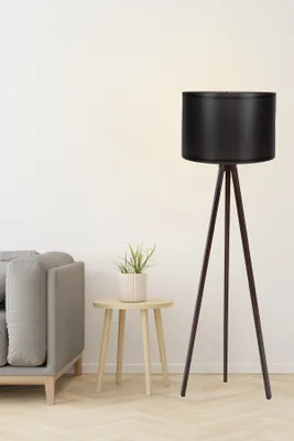 A floor lamp and a small side table with a plant are shown next to a sofa against a plain wall.