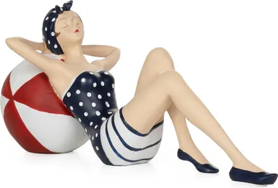 A decorative figurine of a woman in a vintage swimsuit relaxing on a beach ball.