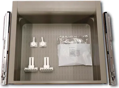 A kitchen cabinet base drawer with accompanying hardware, including drawer slides and mounting brackets, laid out inside the drawer.