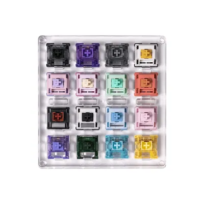 A grid of 16 different colored mechanical keyboard switches arranged in a clear acrylic holder.