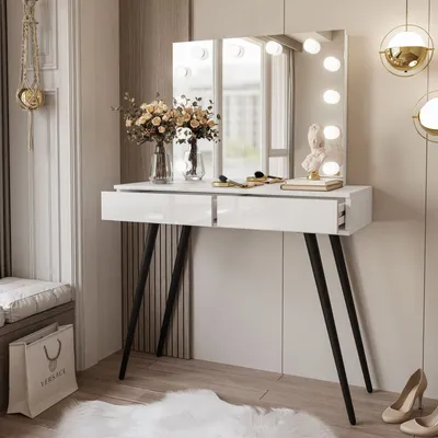 A modern white vanity desk with a lighted mirror, decorated with flowers and makeup accessories, placed in a well-lit room.