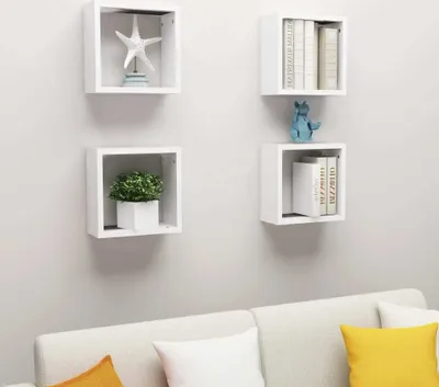 Four white cube shelves mounted on a light gray wall above a white sofa with yellow and white cushions.