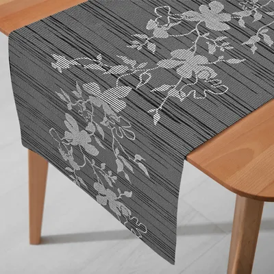 A table runner with a floral pattern is laid out on a wooden table.