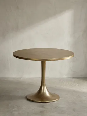 Freigestellter goldener Designtisch aus Aluminium mit rundem Trompetenfuß, Frontalansicht der skulpturalen Silhouette auf weißem Hintergrund._#sku_SAFWL7.132#
