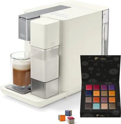 A white Tchibo Qbo coffee machine with a glass of coffee and a box of coffee capsules.