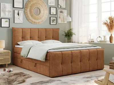 A bedroom scene featuring a king-size boxspring bed with a tufted headboard and storage drawers, styled with bedding and decorative elements.