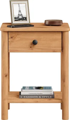 A wooden nightstand with a drawer and an open shelf. A framed picture and a round object are on top of the drawer, and books are on the shelf.