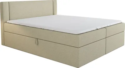 A beige boxspring bed with a white sheet on top, shown from a side-angle.