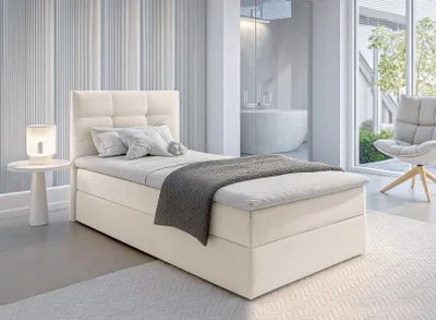 A modern bedroom with a beige bed, a bedside table with a lamp, and a chair near a large window.