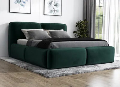 A green upholstered bed with pillows and a blanket on a rug in a room.