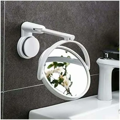 A white cosmetic mirror with a suction cup mount is attached to a gray tiled wall above a white sink and faucet.