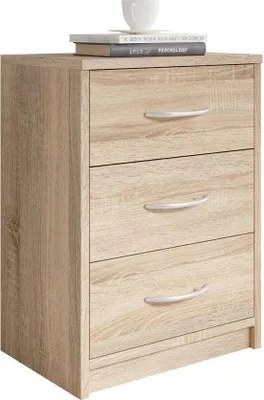 A three-drawer nightstand with a light wood finish and silver handles, topped with two books and a white mug.
