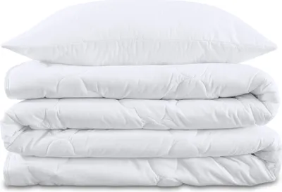 A stack of white bedding, including a pillow and two folded duvets, is presented against a white background.