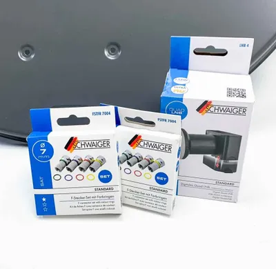Several product packages and a satellite dish component are arranged on a white surface.