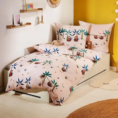 A child's bed with bedding featuring a sloth and palm tree pattern.