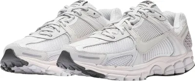 A pair of white and gray Nike Zoom Vomero 5 sneakers are shown from a slightly elevated side angle against a white background.