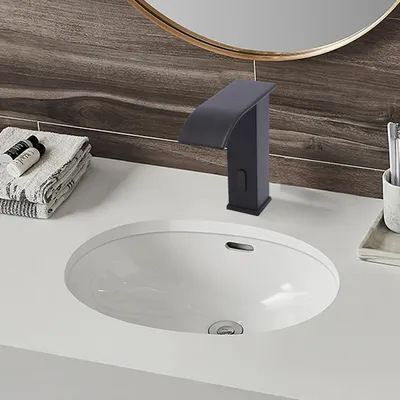 A modern bathroom sink with a black faucet and folded towels.