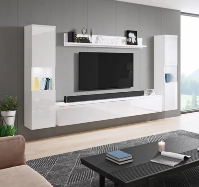 A modern white entertainment center with a large black television, soundbar, and decorative items, displayed in a living room setting.