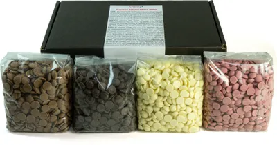 Four bags of chocolate drops in different colors are arranged in front of a black box.