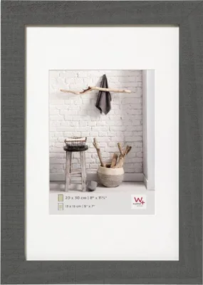 A framed picture of a rustic interior scene with a stool, basket, and decorative branches.