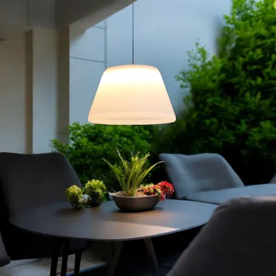 An outdoor patio setting with a table, chairs, plants, and a hanging pendant lamp.