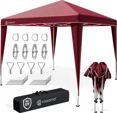 A red pop-up gazebo with accessories laid out around it, including ropes, hooks, and a carrying bag.