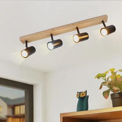 A ceiling light fixture with four adjustable spotlights mounted on a wooden beam, installed on a white ceiling.