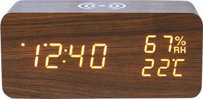 A digital alarm clock with a wood-grain finish displays the time, humidity, and temperature.
