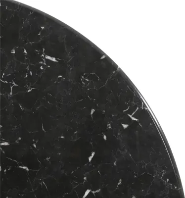 A close-up view of a black marble tabletop with white veining, showing the edge of a round surface.