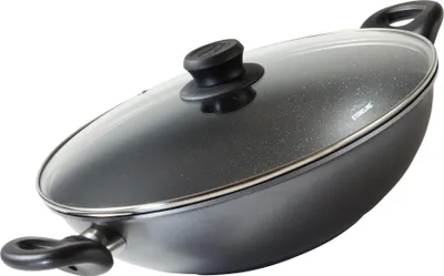 A black wok pan with a glass lid and silver trim, shown from a diagonal angle against a white background.