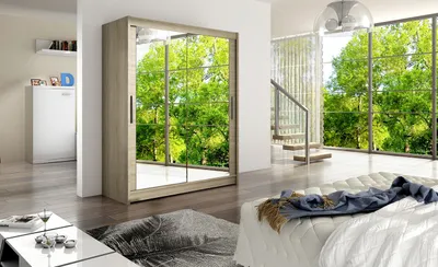 A bedroom with a large wardrobe with mirrored doors reflecting a green outdoor scene. A bed with white bedding and a blue throw is in the foreground.