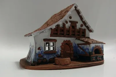 Keramikminiatur eines ländlichen Hauses. Das Haus ist in Braun- und Weißtönen gehalten. Braunes Dach