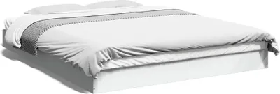 A white bed frame with white bedding and a gray and white patterned throw blanket.