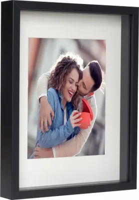 A framed photo of a couple, with the man kissing the woman's cheek as she opens a gift.