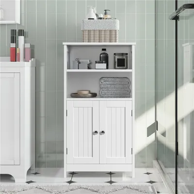 A white bathroom cabinet with two doors, positioned in a bathroom with light green tiled walls.
