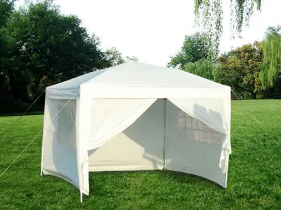 A white gazebo tent set up on a grassy lawn with trees in the background.