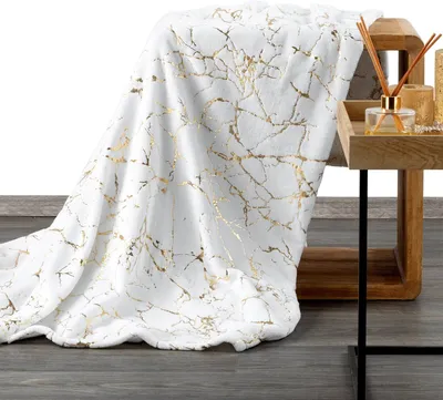 A white blanket with a gold marble pattern is draped over a wooden side table.