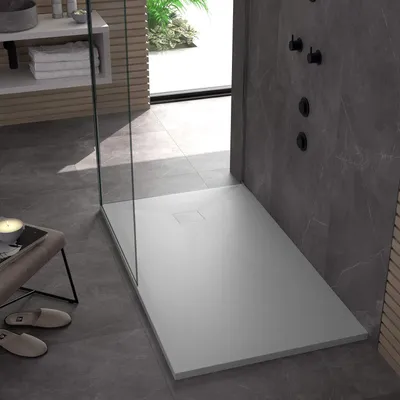 A modern bathroom with a white shower tray, gray tiled walls, and a glass shower enclosure.