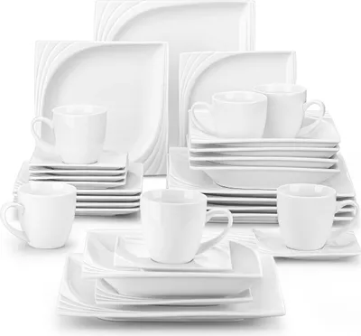 A collection of white ceramic dinnerware, including plates, bowls, and cups, neatly arranged.
