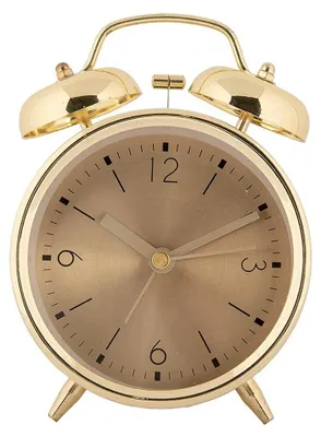A close-up studio shot of a gold-colored analog alarm clock.