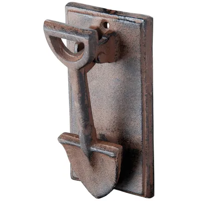 A cast iron door knocker shaped like a spade, mounted on a rectangular plate.