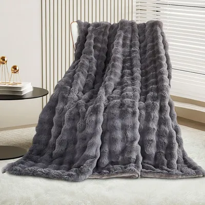 A dark gray plush blanket draped over a chair in a room.