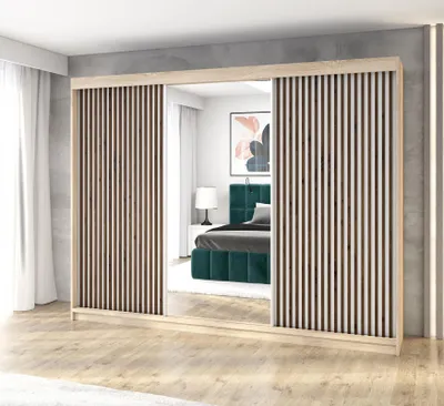 A bedroom scene with a large wardrobe featuring mirrored doors and slatted panels, reflecting a bed with a green headboard.